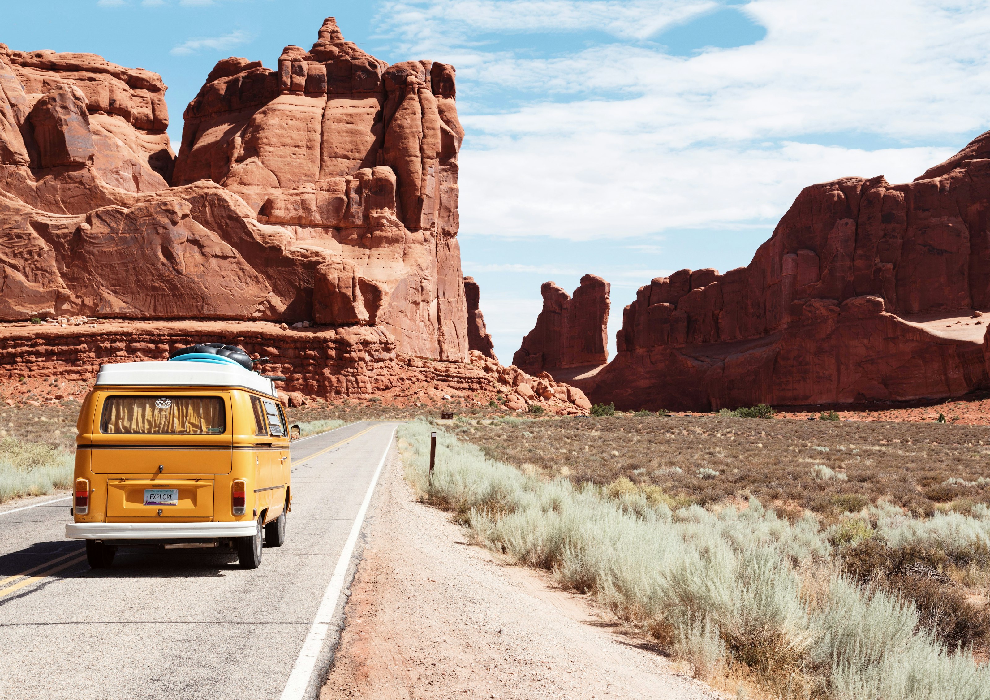 A vintage camper van on a desert road between red rock formations