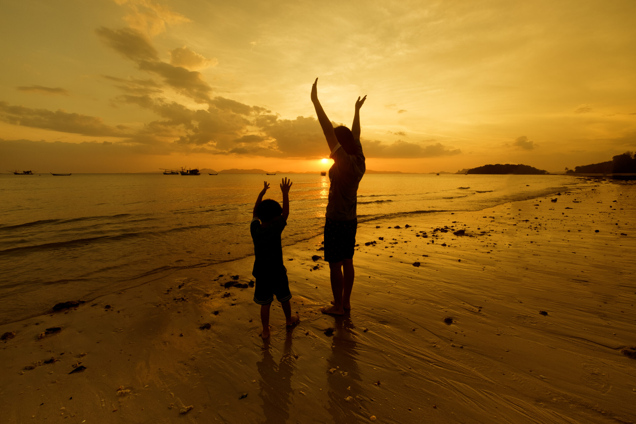 A mother and son playing on the beach and sea outdoors at sunset in happy holiday vacation time with copy space